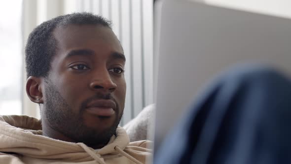 Close Up Of Young Man Relaxing At Home Lying On Sofa Using Laptop To Work From Home Or Shop Online