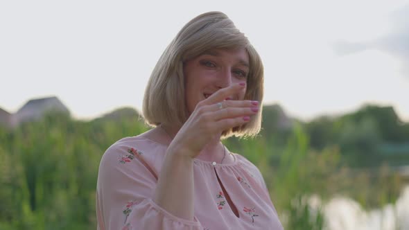 Closeup Portrait of Cheerful Trans Woman Posing in Sunrays Stretching Hand to Camera Smiling