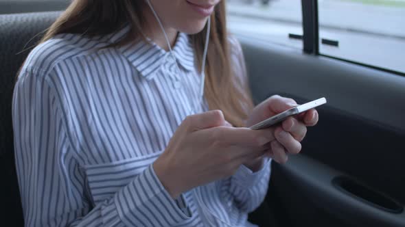Woman Sitting in Backseat Car in Taxi Listen Music and Use Smartphone