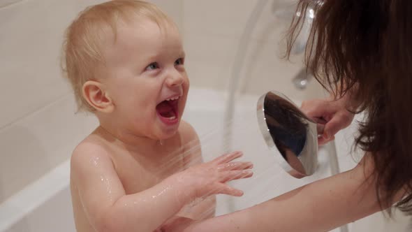 Happy Kid Laughing While Taking Shower in Bathroom Mother Pouring Water on Her One Year Old Baby