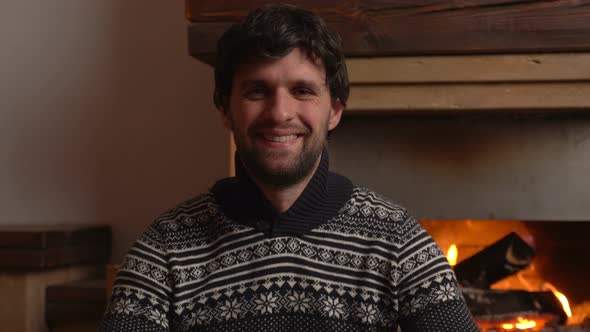 Portrait of Man Looking at Camera on the Background of the Fireplace