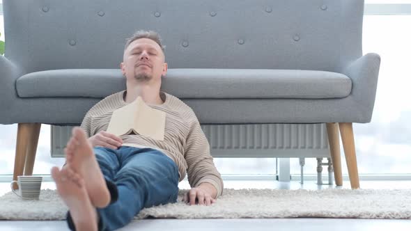 Man Reading Book on a Floor at Home