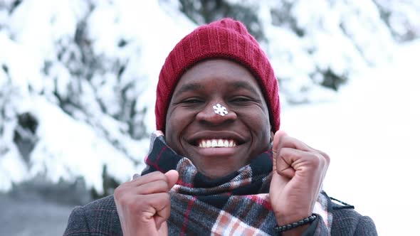 Excited Hispanic Man in Red Hat with Snowflake on Face Having Fun and Feeling Christmas Mood in Park