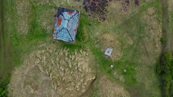 Top-down aerial view over marram grass anchored dunes and abandoned building