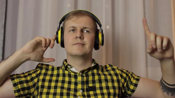 Man Sitting on the Sofa Listens Music From Wireless Headphones and Dances