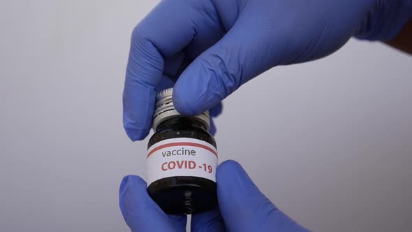 Shot of doctor opening covid-19 vaccine bottle cap