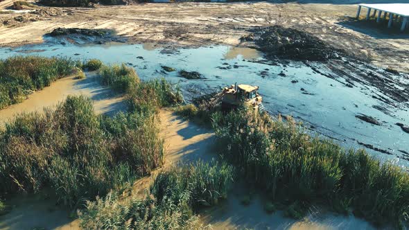 Aerial View Large Bulldozer Cleans the Bottom of the Lake From Thickets and Swamps