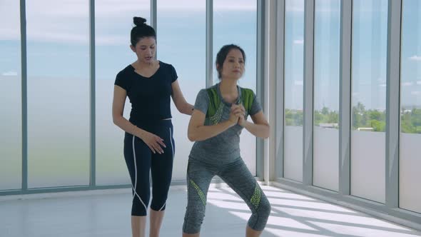 Exercise concept. Two fitness women doing squat exercise workout indoor. 4k Resolution