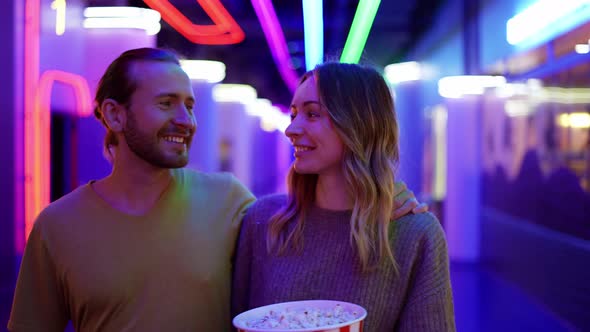 Happy Young Caucasian Woman and Man Walking By Cinema Hall Hugging and Chatting