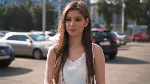 Attractive Woman in White Blouse Walks Along Parking Area