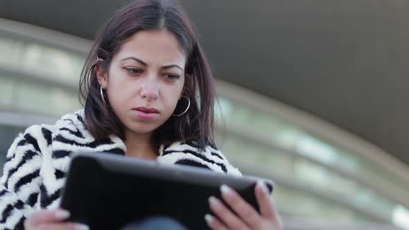 Thoughtful Young Woman Looking at Tablet Outdoor