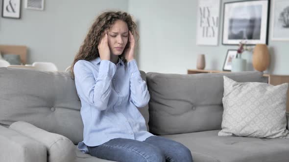 Curly Hair Woman with Headache Sitting Tense on Couch