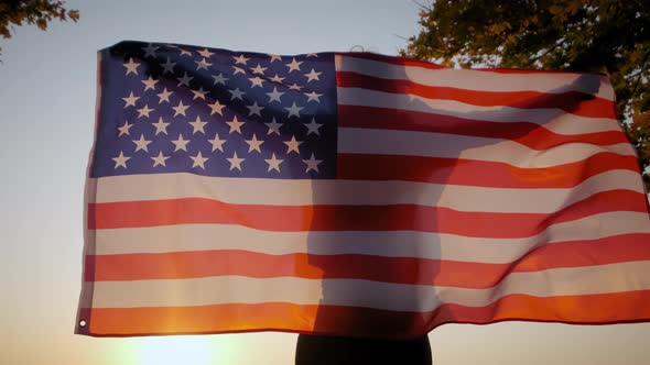 Back View of Happy Woman with USA National Flag Standing Outdoors at Sunset