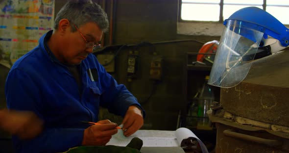 Male worker writing on clipboard in foundry workshop 4k