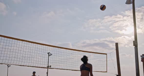 Slow motion of women playing beach volleyball during sunset