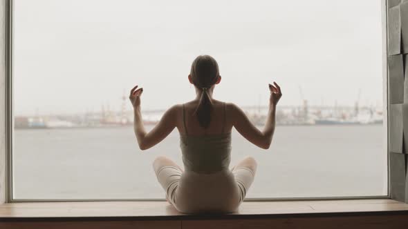 Woman Meditating in front of Panoramic Window