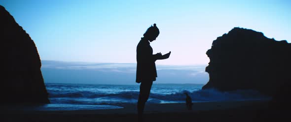 A man writing a letter on the beach and his dog running