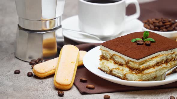 Portion of Traditional Italian Tiramisu dessert and cup of coffee on grey concrete background