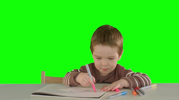 A Son Drawing at the Table at Home on a Green Screen