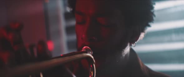 Close up of a trumpeter playing in backlit and red neon lights