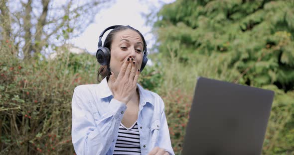 Woman with headphones ending video call with blow kiss