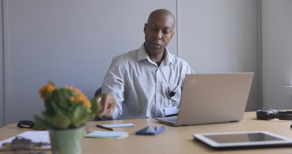 Businessman using laptop in office and taking notes