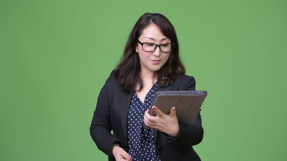 Mature Beautiful Asian Businesswoman Looking Shocked While Using Digital Tablet