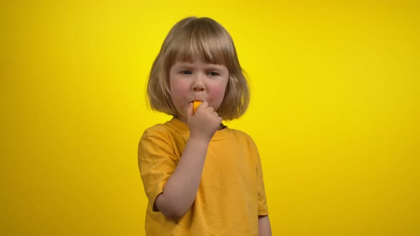 A Cute Little Girl with Short Hair is Blowing in a Whistle on a Camera