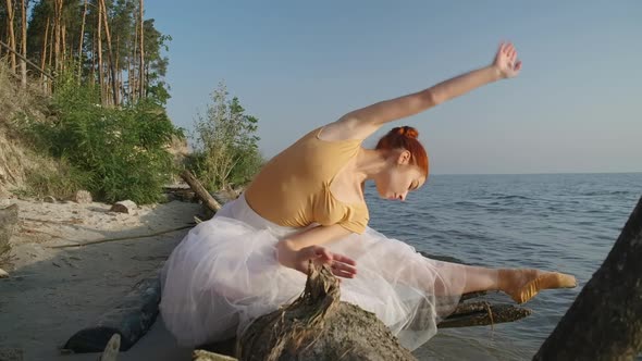 Portrait of Flexible Graceful Ballerina Bending in Slow Motion Sitting on Tree Trunk on River Bank