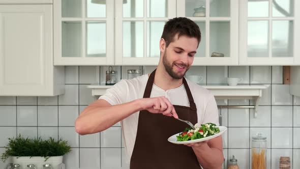 An Attractive Man in an Apron Tastes a Cooked Vegan Salad and Enjoys It