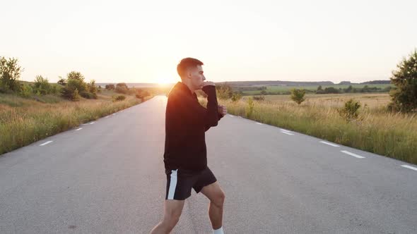 Persistent Kickboxer Training Kicks on Country Road Singly During Sunset