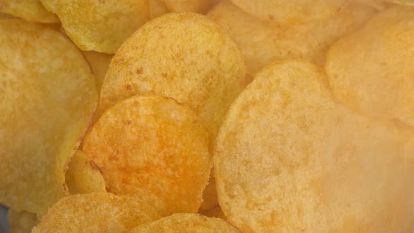 Crispy hot potato chips with smoke rotating in macro. Golden fried potatoes close up. Potato snack