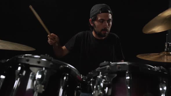 Young Man Playing on Drum Kit Over Black Background Slow Motion