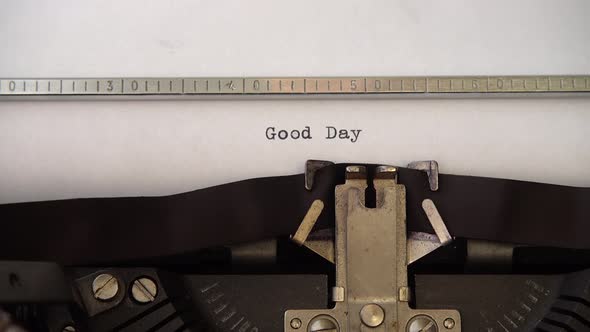 Typing phrase Good Day on retro typewriter. Close up.