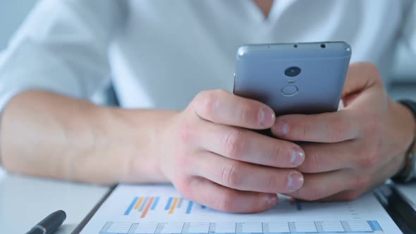 Financial Auditor Sitting In Office And Using Mobile Smart Phone.