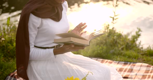 Black Woman in White Dress Reading at the River Bank