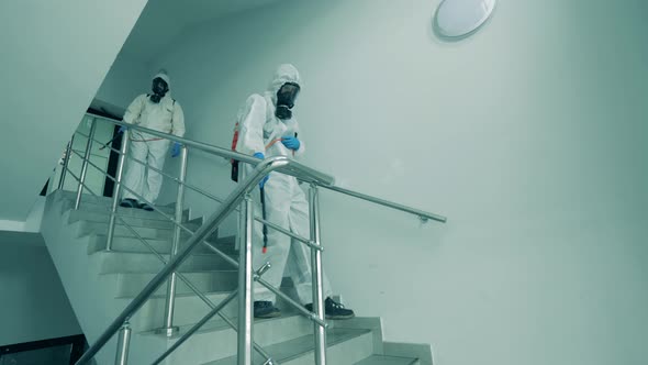 Men in Protective Suits Disinfect Stairs with Sprayers