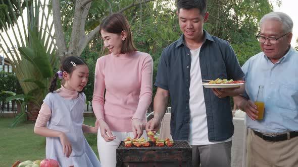 Happy Asian family having a barbecue-BBQ party together in the garden at home.