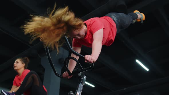 Group of Smiling Friends Women Class Exercising Training Spinning on Stationary Bike at Modern Gym