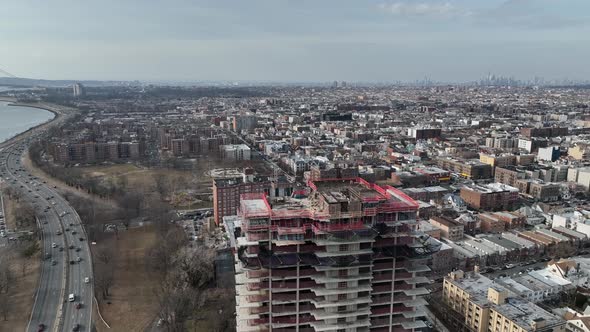 A high angle view above a new high-rise construction site with Shore Parkway and the Verrazano bridg