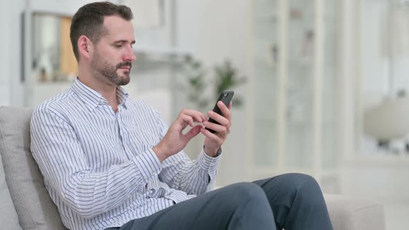 Attractive Young Man Using Smartphone at Home 