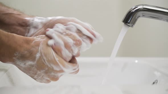 Person washing hands with soap in sink, avoid covid-19 coronavirus transmission