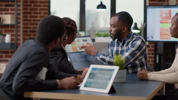 Team of African American Employees Analyzing Financial Charts on Laptop