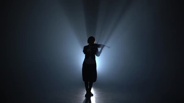 Girl Plays the Violin a Classic Composition in a Dark Smoky Room