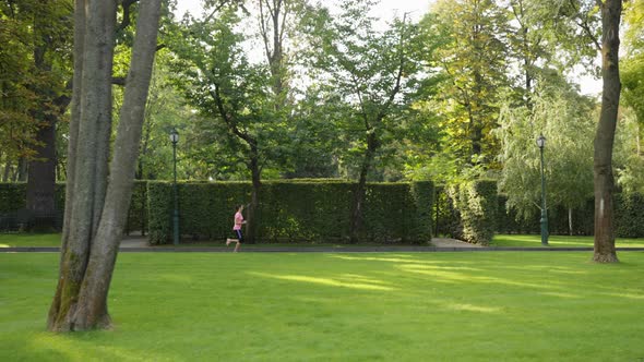 Sporty Woman Jogging Against Garden Maze