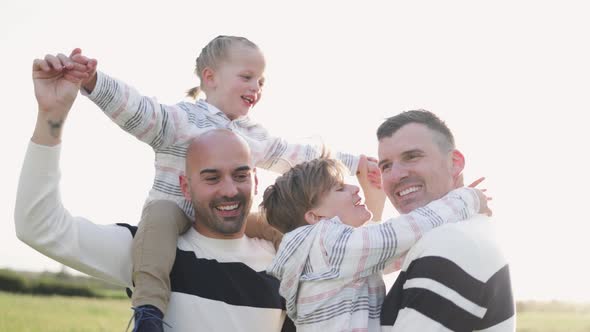 Gay male parents having fun with their sons outdoor in summer day - Lgbt diversity family concept