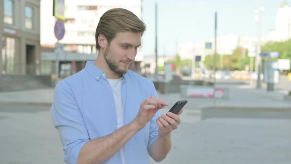 Man Celebrating Online Success on Smartphone Outdoor