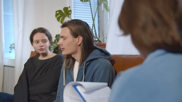 Millennial Couple Sitting on Couch Visiting Female Psychologist