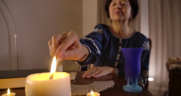 Close-up of Female Caucasian Hand Lighting Up Candle Standing at the Foreground