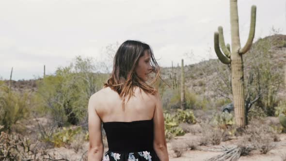 Young Tourist Woman with Flying Hair Walking at Saguaro Cactus